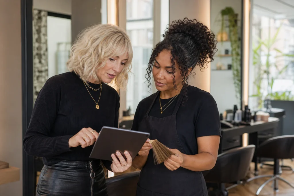 Two colourists reviewing structured salon colour handover notes together